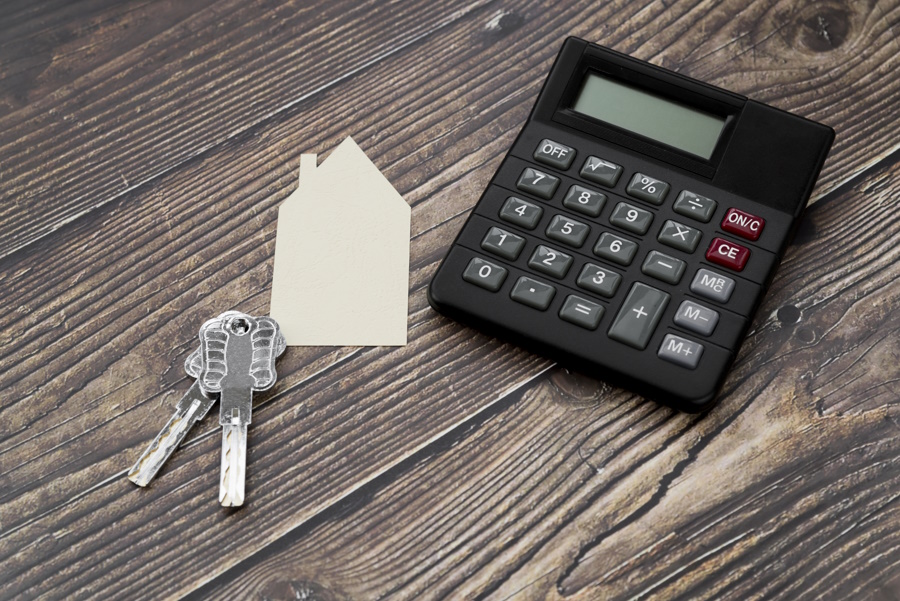 paper-cut-out-house-with-keys-calculator-wooden-textured-surface